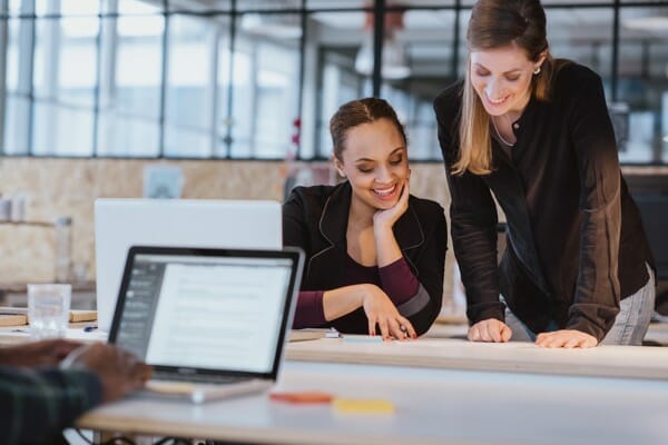 two-young-woman-at-office-working-on-a-new-creative-design-diverse-team-of-professionals-looking-at-a-document-smiling_BaliVH4tl