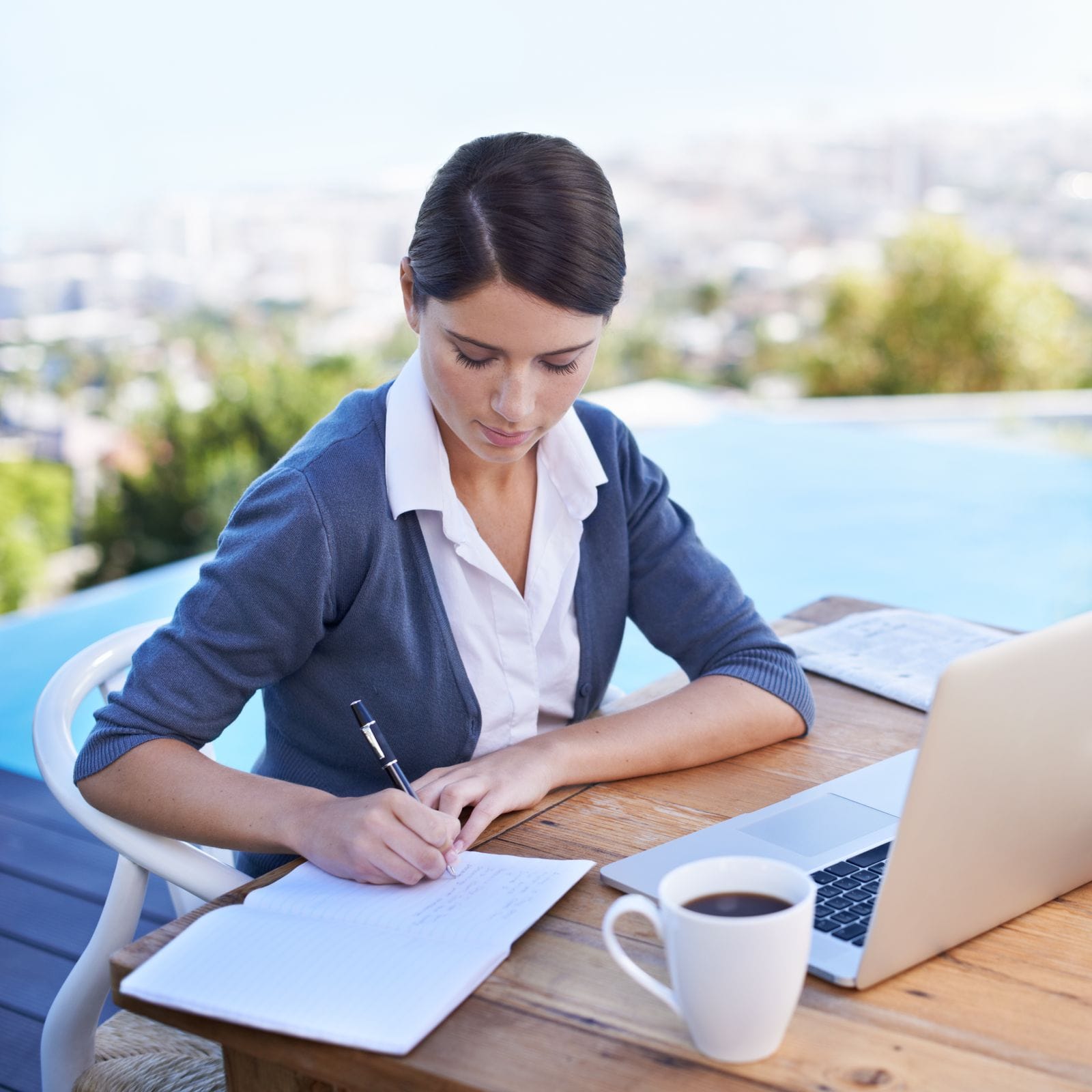 49750580_taking-notes-a-young-businesswoman-working-on-her-laptop-by-a-swimming-pool